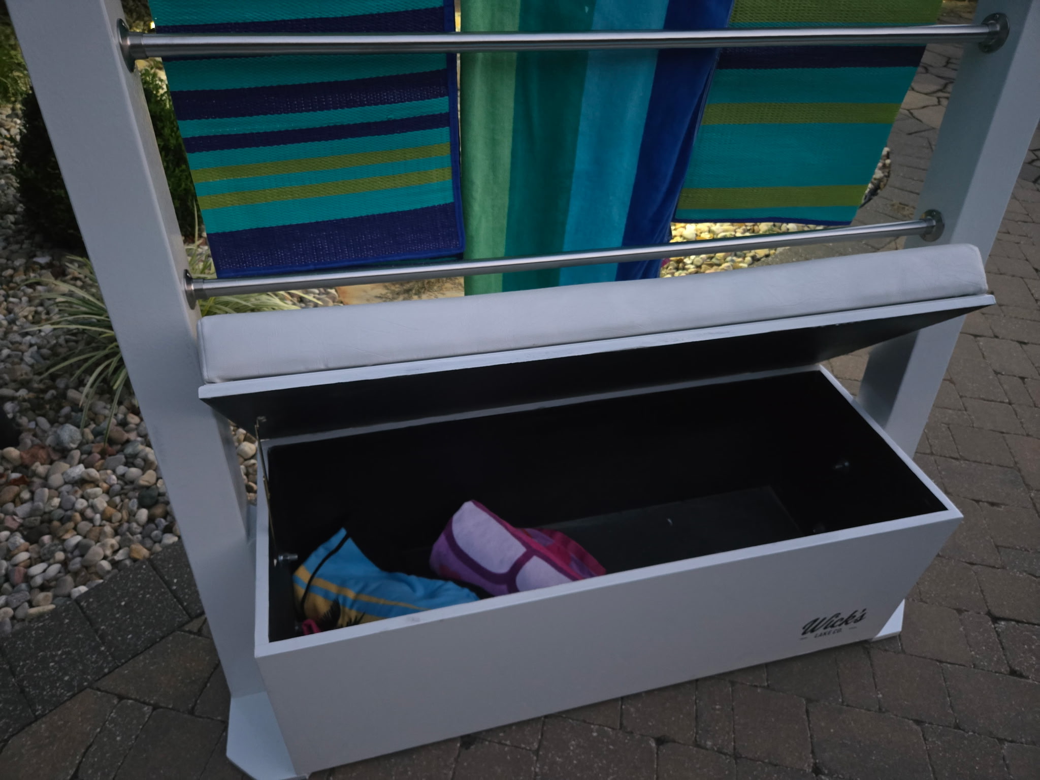 The Drydock seat open, showing interior storage under hanging towels